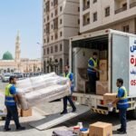 شاحنة نقل أثاث حديثة تقف أمام مبنى سكني في المدينة المنورة أثناء تحميل العفش